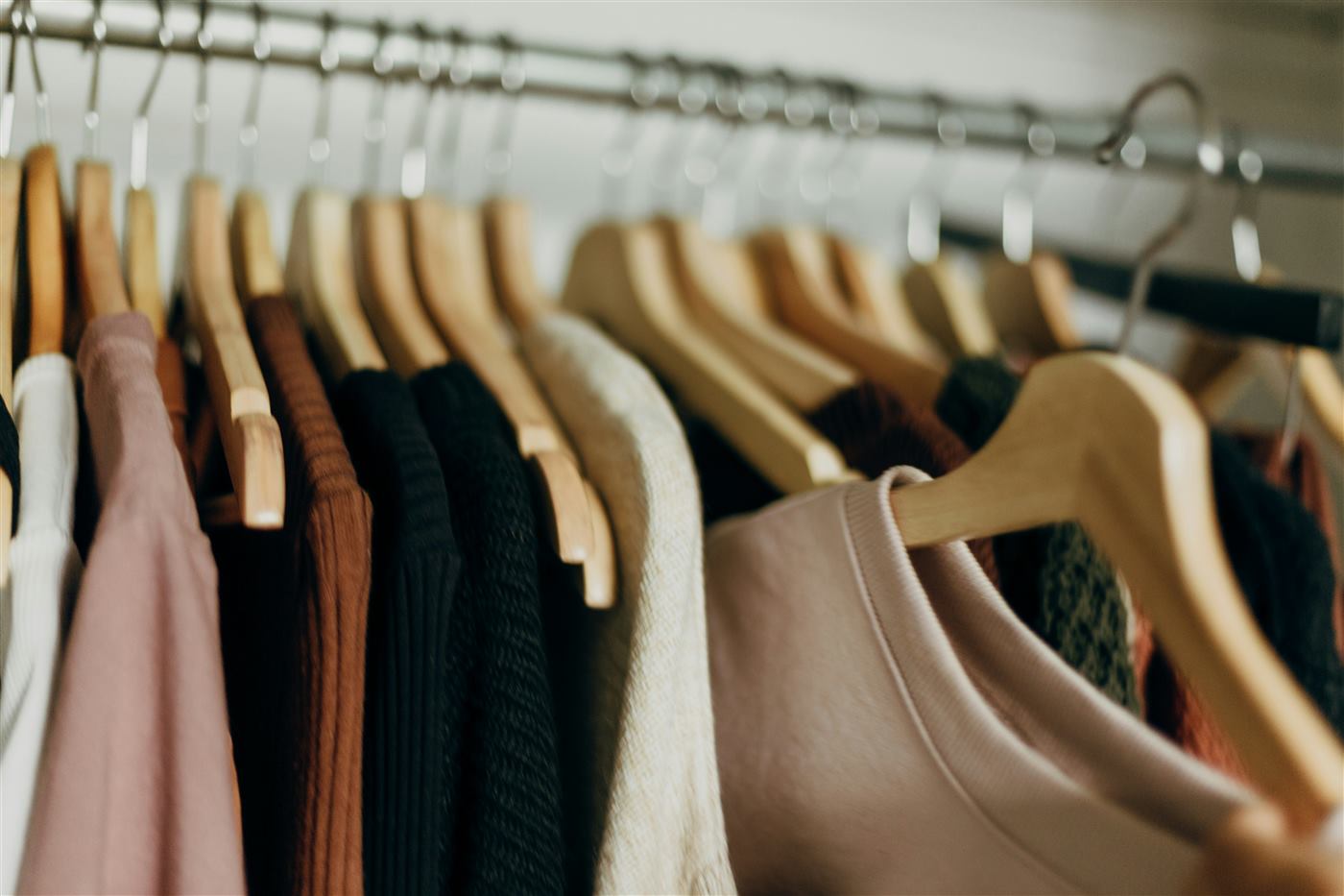 Clothes hanging on matching wooden hangers in a closet
