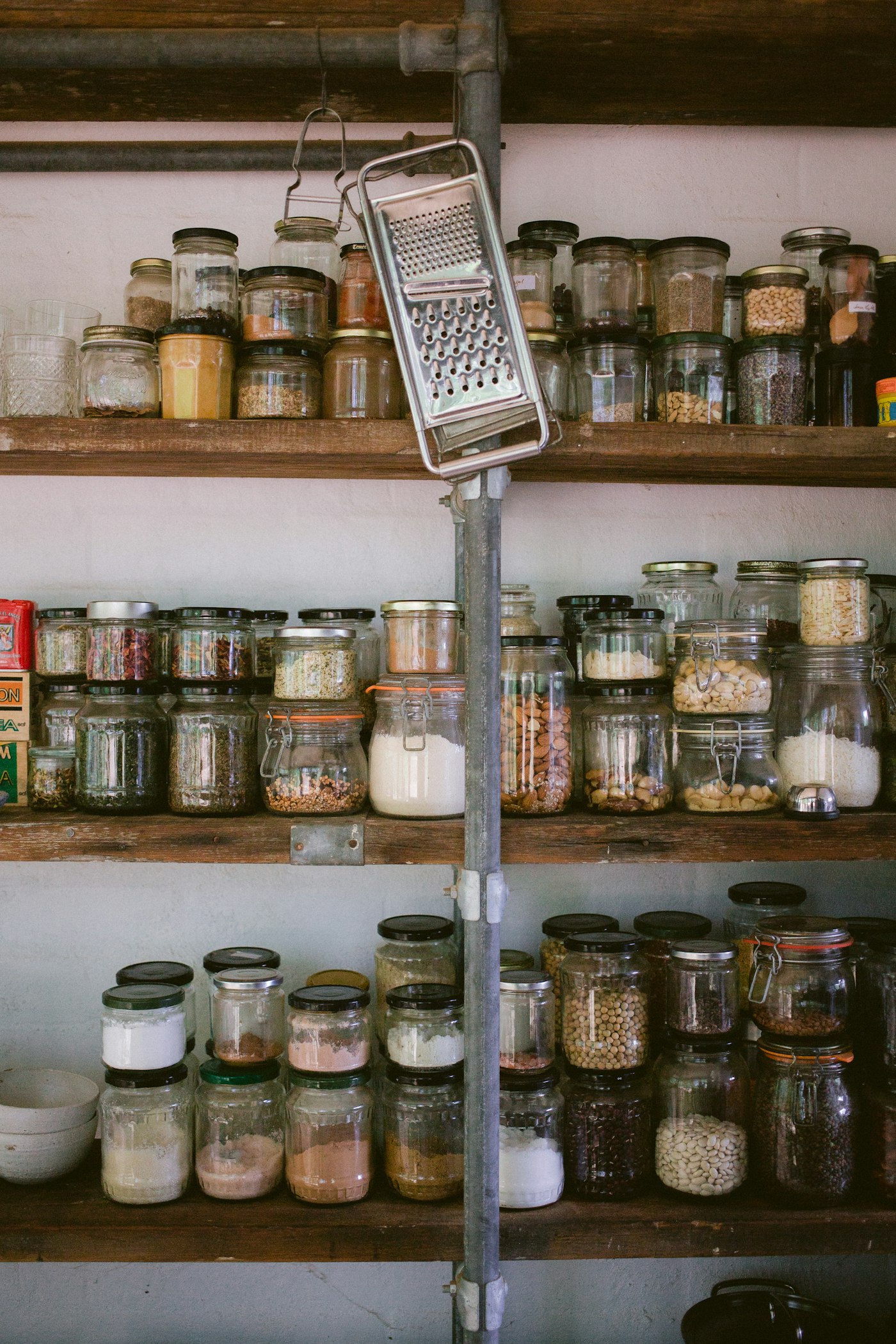 Wooden pantry shelves lined with glass jars of dry goods and spices