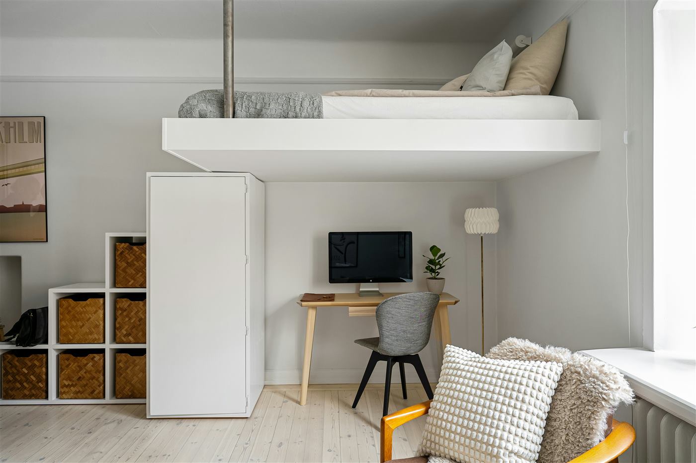 Small studio apartment with a loft bed above a desk and cube storage